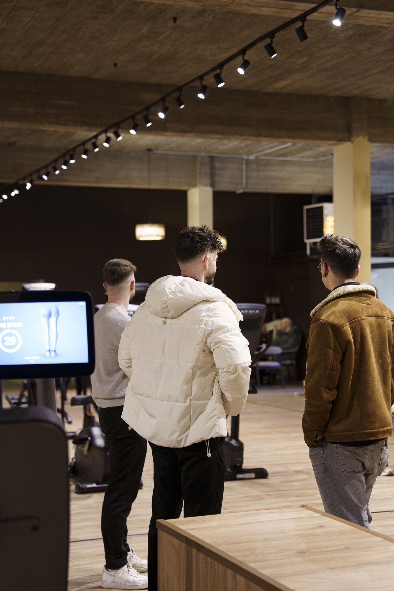 Een coach legt het EGYM-scherm uit aan leden