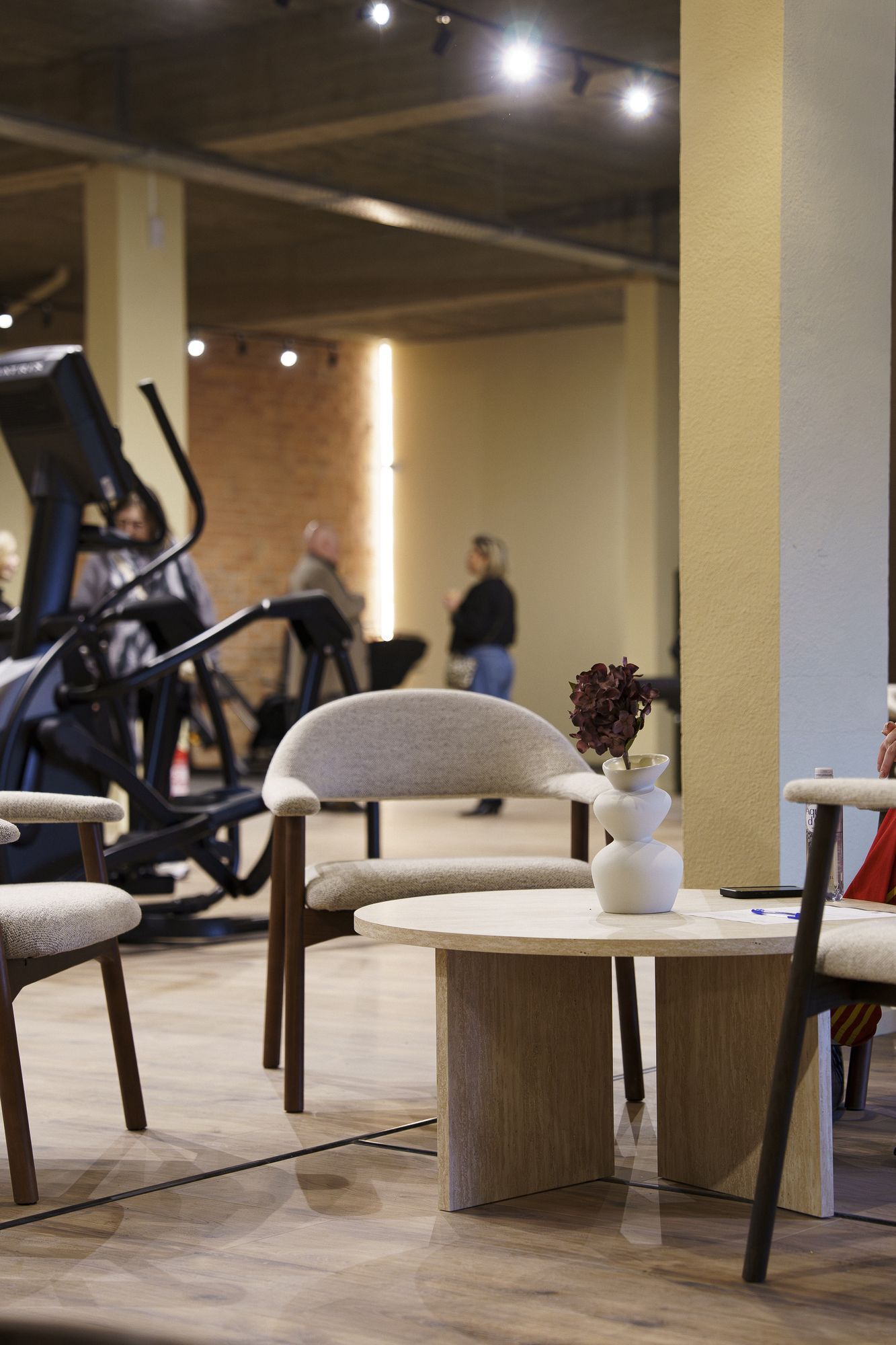 Lounge met ronde tafel en fauteuils naast de cardiozone