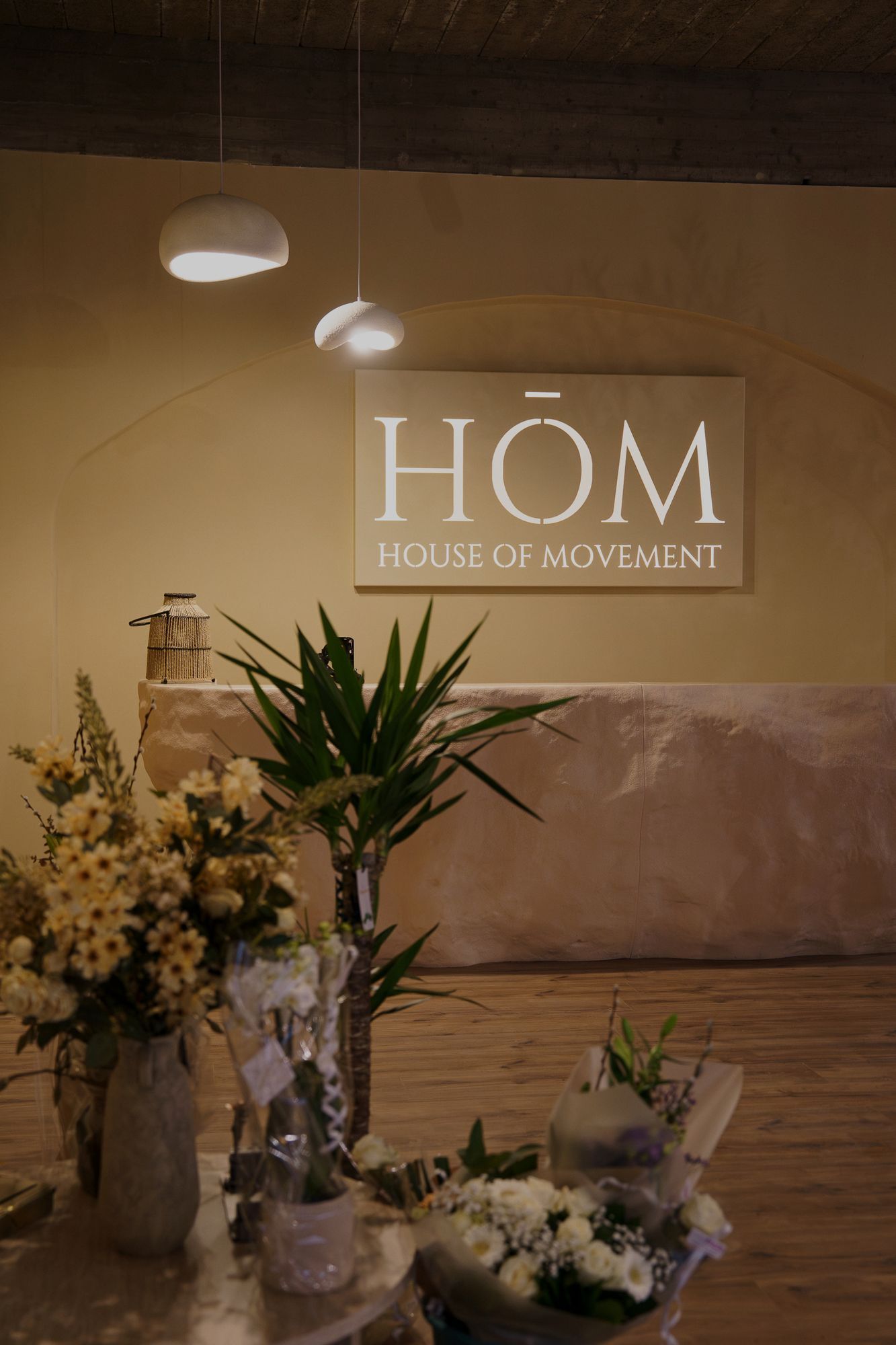 Het onthaal van HŌM met het logo aan de muur, bloemen en warme verlichting